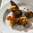 Gegrillte Muscheln mit einer goldenen Kruste auf weißem Teller
