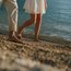 Barfuß am Kiesstrand spazierende Personen am Meer